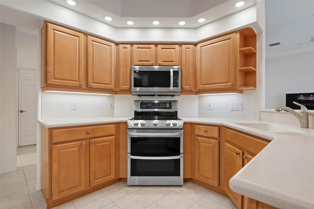 kitchen with tasteful backsplash, sink, light tile patterned floors, kitchen peninsula, and stainless steel appliances