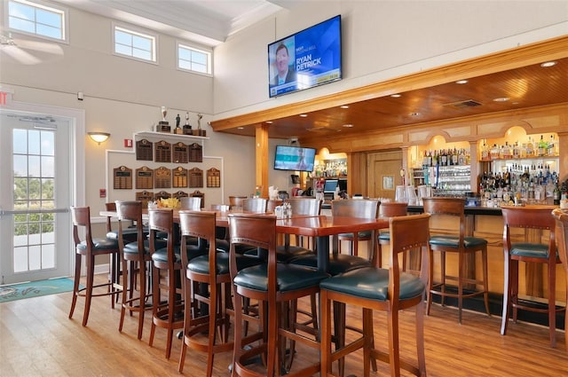 bar featuring crown molding, a high ceiling, and light wood-type flooring