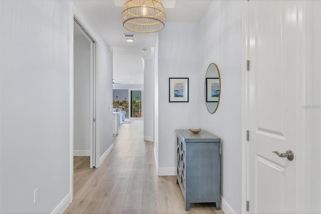 hall featuring a chandelier and light hardwood / wood-style floors