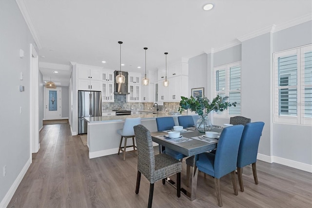 dining room with sink, light hardwood / wood-style flooring, and ornamental molding