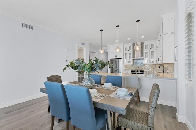 dining room featuring ornamental molding and light hardwood / wood-style floors