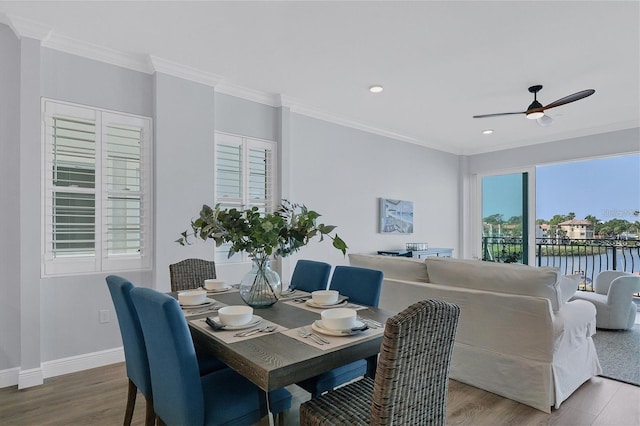 dining room with hardwood / wood-style floors, ornamental molding, ceiling fan, and a water view