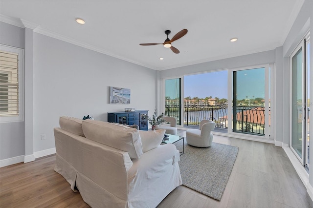 living room featuring a water view, ceiling fan, crown molding, and light hardwood / wood-style flooring