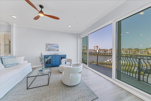 living room with crown molding, light hardwood / wood-style floors, ceiling fan, and a water view