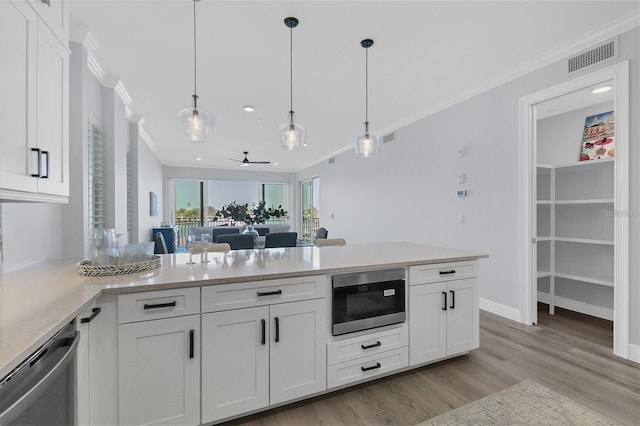 kitchen with built in microwave, white cabinetry, pendant lighting, and stainless steel dishwasher