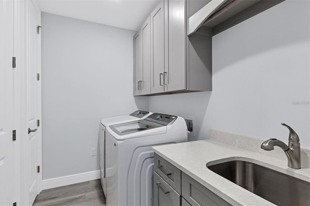 laundry room with separate washer and dryer, sink, light hardwood / wood-style floors, and cabinets