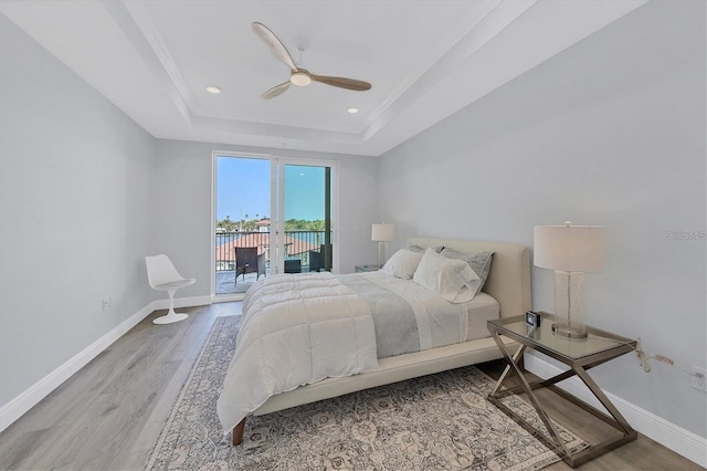 bedroom with a raised ceiling, wood-type flooring, access to exterior, and ceiling fan