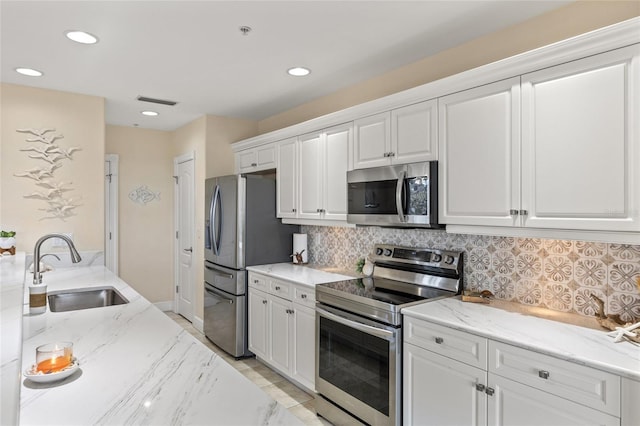 kitchen with white cabinetry, sink, decorative backsplash, light stone counters, and stainless steel appliances