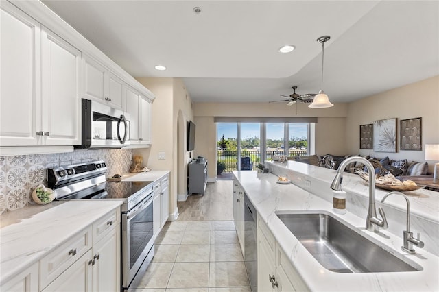 kitchen featuring pendant lighting, sink, white cabinetry, stainless steel appliances, and decorative backsplash