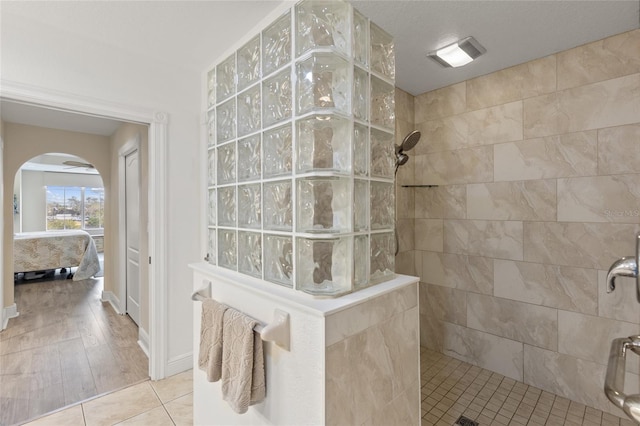 bathroom featuring tiled shower and tile patterned flooring