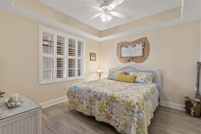 bedroom featuring hardwood / wood-style flooring, a raised ceiling, and ceiling fan