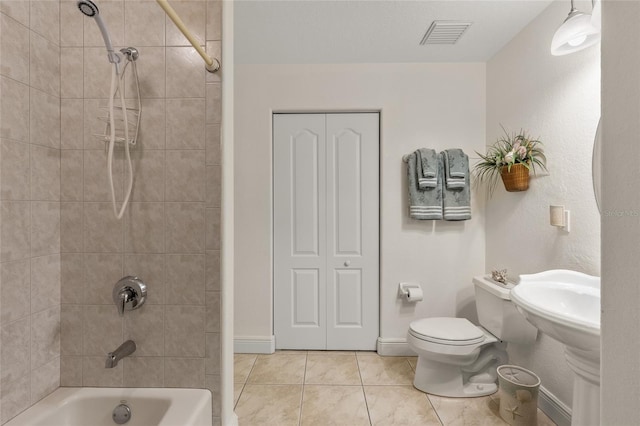 bathroom featuring toilet, tiled shower / bath combo, and tile patterned flooring