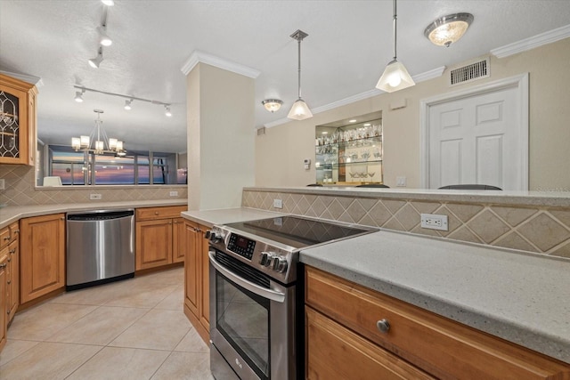 kitchen featuring hanging light fixtures, crown molding, appliances with stainless steel finishes, and light tile patterned floors