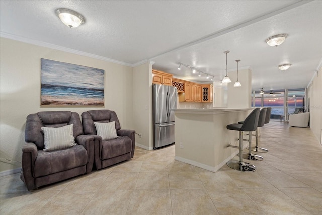 kitchen with stainless steel fridge, a kitchen breakfast bar, a center island, ornamental molding, and a textured ceiling