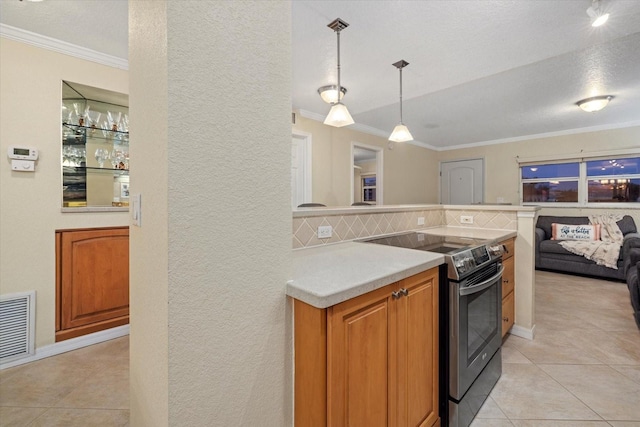 kitchen with light tile patterned floors, crown molding, backsplash, stainless steel electric range oven, and decorative light fixtures