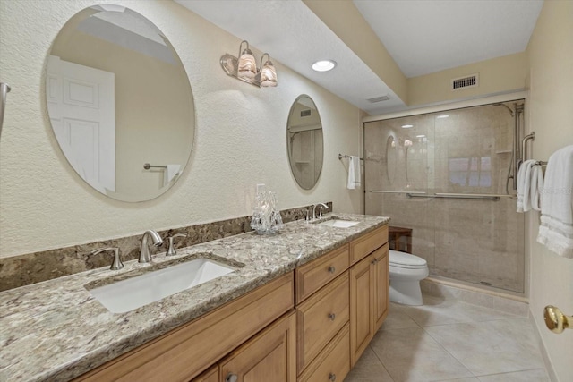 bathroom with a shower with door, vanity, tile patterned floors, and toilet