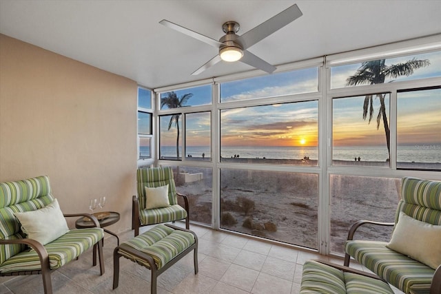 sunroom / solarium with ceiling fan and a water view