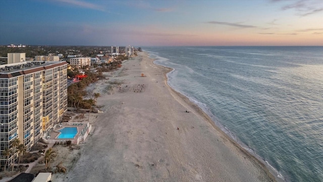 aerial view at dusk with a view of the beach and a water view