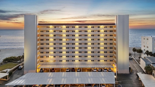 outdoor building at dusk featuring a beach view and a water view