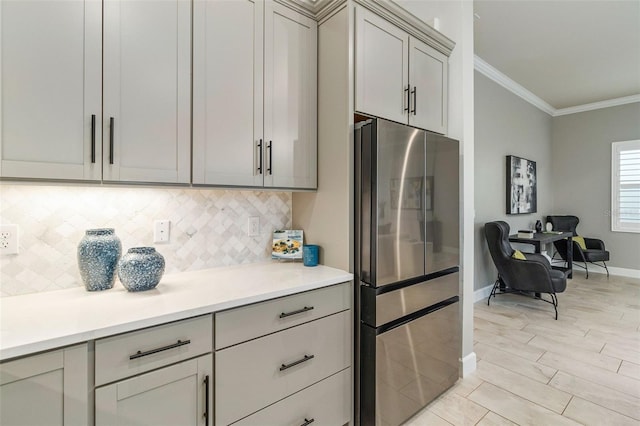 kitchen featuring tasteful backsplash, crown molding, gray cabinets, and stainless steel fridge