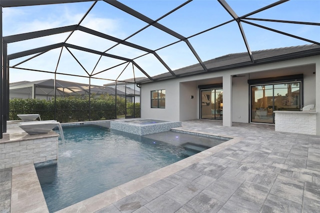 view of swimming pool featuring a patio area, pool water feature, glass enclosure, and an in ground hot tub