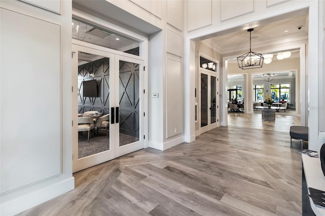 entryway featuring crown molding, parquet floors, a chandelier, and french doors