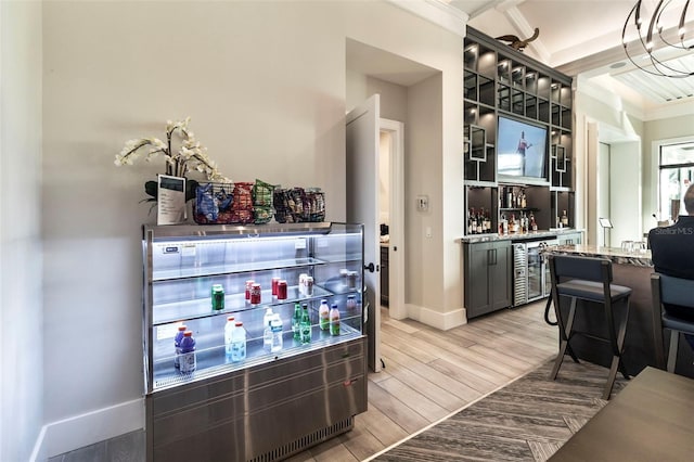 bar with wine cooler, crown molding, vaulted ceiling, light wood-type flooring, and light stone countertops