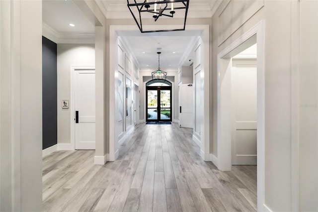 corridor featuring crown molding, light hardwood / wood-style floors, and french doors