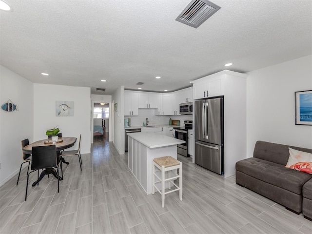 kitchen featuring sink, a breakfast bar area, a center island, stainless steel appliances, and white cabinets