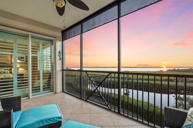 sunroom featuring a water view and ceiling fan