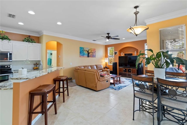 interior space with ornamental molding, a wealth of natural light, ceiling fan, and light tile patterned flooring