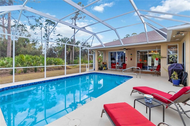 view of swimming pool featuring ceiling fan, a patio area, and glass enclosure