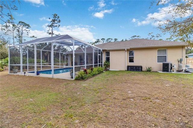 rear view of property featuring glass enclosure and a lawn