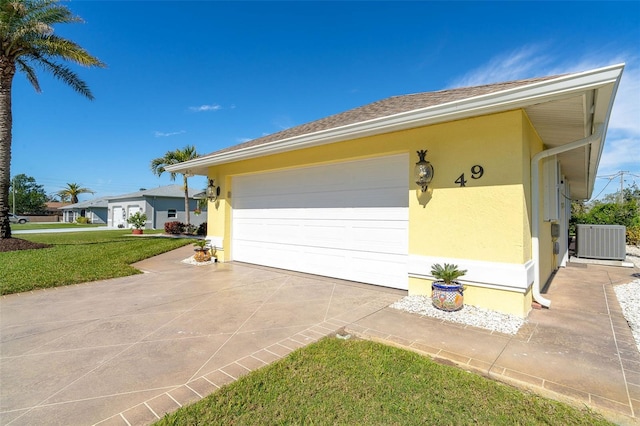 view of home's exterior with central AC unit, a garage, and a yard