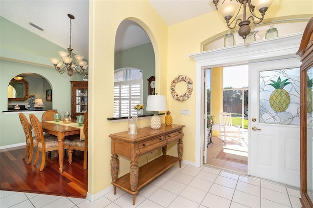 foyer entrance with vaulted ceiling, light tile patterned floors, and a notable chandelier