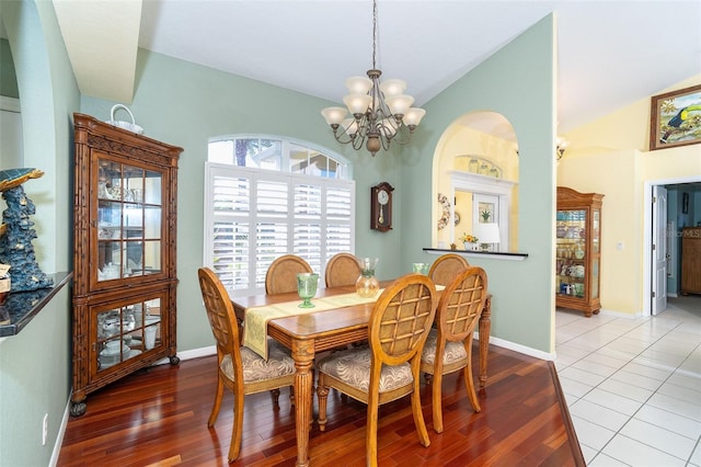 dining space featuring light hardwood / wood-style flooring, a notable chandelier, and vaulted ceiling