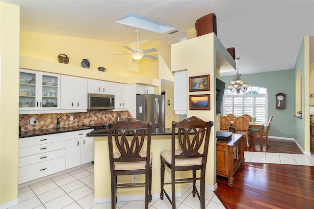 kitchen with white cabinetry, stainless steel appliances, a breakfast bar area, and backsplash