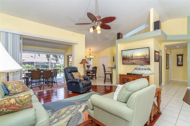 living room with ceiling fan with notable chandelier, lofted ceiling, and light tile patterned floors