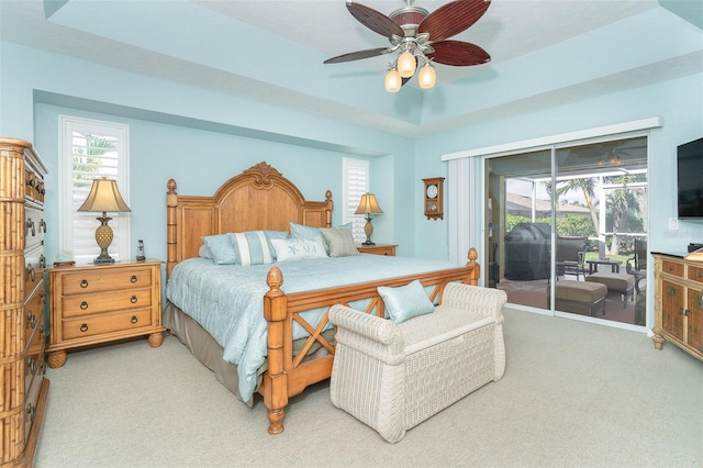 bedroom featuring a raised ceiling, light colored carpet, access to exterior, and ceiling fan