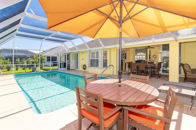 view of swimming pool featuring a patio, ceiling fan, and glass enclosure