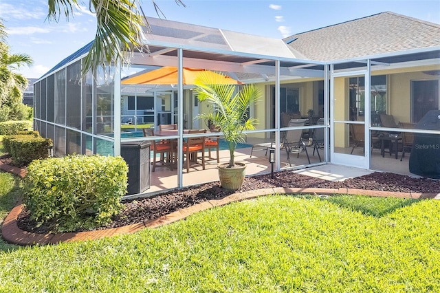 rear view of property with a lanai, a patio area, and a lawn