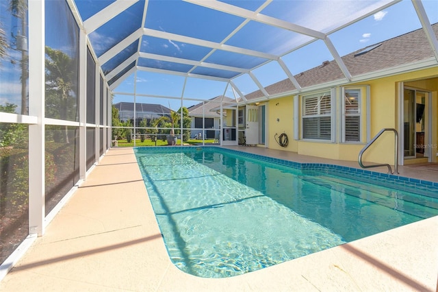 view of pool with glass enclosure and a patio area