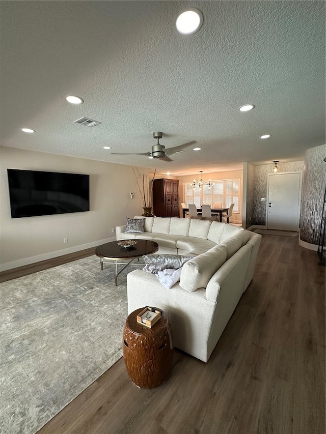 living room featuring ceiling fan, dark hardwood / wood-style flooring, and a textured ceiling