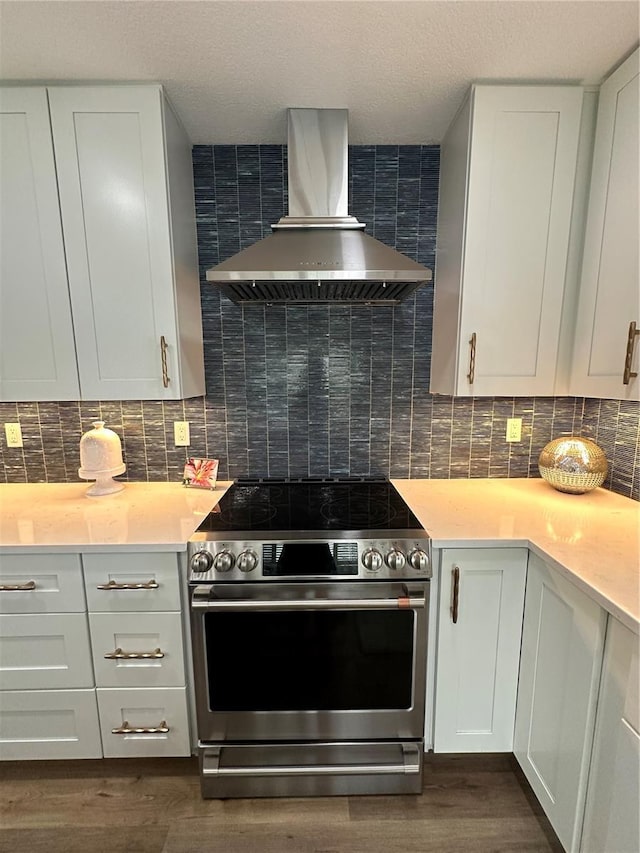 kitchen featuring stainless steel electric stove, white cabinets, dark hardwood / wood-style flooring, decorative backsplash, and wall chimney range hood