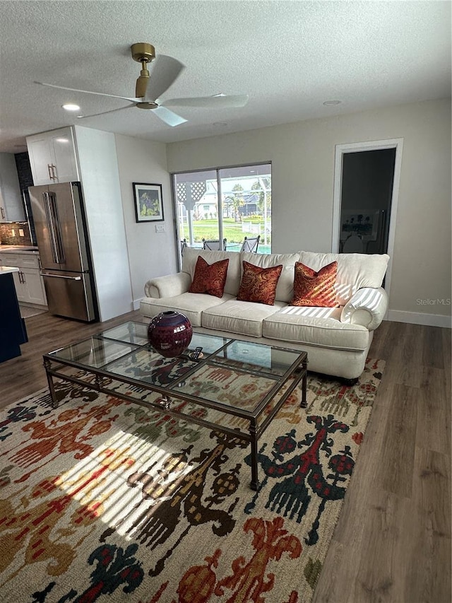 living room with ceiling fan, dark hardwood / wood-style flooring, and a textured ceiling