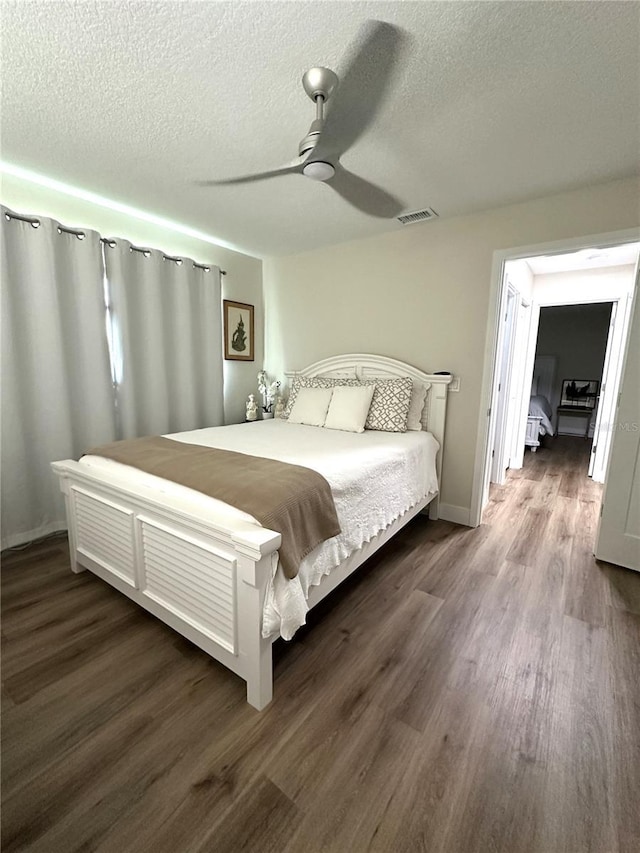 bedroom featuring a textured ceiling, dark wood-type flooring, and ceiling fan