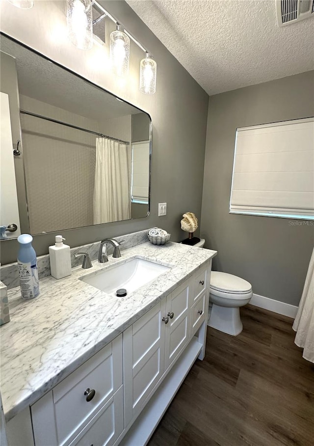 bathroom with vanity, wood-type flooring, a textured ceiling, a shower with curtain, and toilet