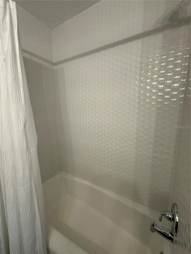 bathroom with shower / bath combination with curtain and a textured ceiling