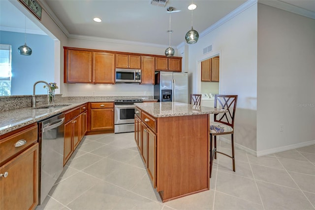 kitchen featuring pendant lighting, sink, light tile patterned floors, stainless steel appliances, and a kitchen breakfast bar