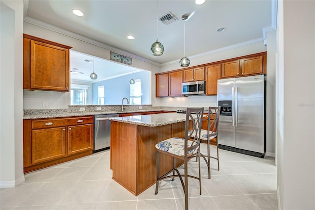 kitchen featuring ornamental molding, appliances with stainless steel finishes, a breakfast bar area, and hanging light fixtures